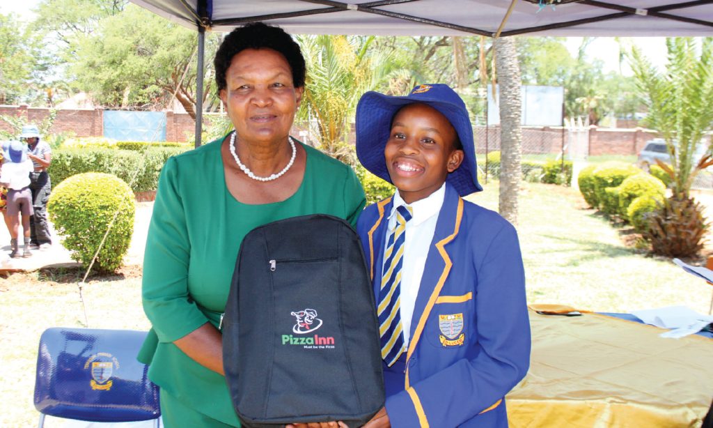 Guest of honour, Bulawayo Central District Schools Inspector, Ms Nozipho Ngulube hands over a prize to Ruvarashe Zimbodza for attaining 6 points in her 2024 Grade 7 exams during the Tennyson Primary School speech and prize-giving day in Bulawayo yesterday