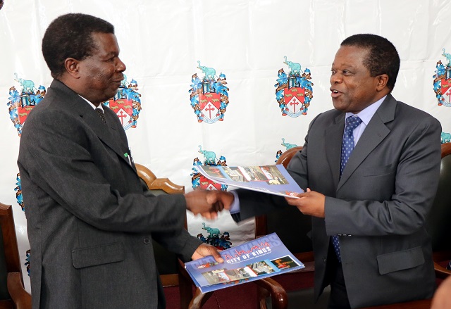 Bulawayo City Council and CBZ Holdings yesterday signed a memorandum of understanding for the implementation of Mahatshula East Housing project. In the picture acting Mayor Councillor Norman Hlabani exchanges documents with CBZ Holdings Divisional Director Mortgage Finance Mr Casper Chibanga at the council chambers yesterday. ( Picture Eliah Saushoma)