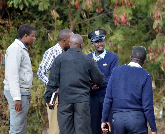 Onlookers restrain a security guard who was charging towards police officers and the driver of a Honda Fit that crashed with his cash in transit van on Friday