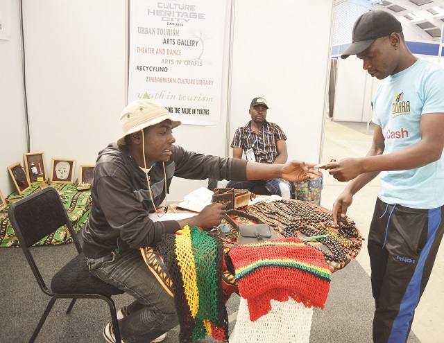 Sydney Gonzoiguru (left) of Culture City Heritage Youths Association shows a visitor to their stand some of their products on display during the Africa Youth in Tourism Conference exhibition at ZITF grounds last week