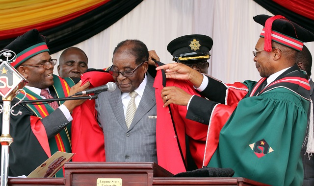 Lupane State University honours President Mugabe with a Doctorate in Agricultural Science at the university's graduation ceremony in Lupane yesterday. Assisting him are the Registrar Jairos Makunde (left) and Vice Chancellor Professor Pardon Kuipa. (Picture by Eliah Saushoma)