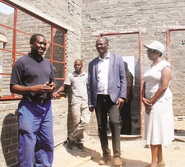 Tshino Village project manager, Mr Davies Takaendesa, explains to the Zanu-PF Politiburo member who is also the Tsholotsho North Member of Parliament, Professor Jonathan Moyo (centre) and Tsholotsho District Administrator Gladys Zizhou (centre) during a tour of the site to assess the progress made on the construction of the Tsholotsho flood victims' houses at Tshino Village in Tsholotsho North on Tuesday