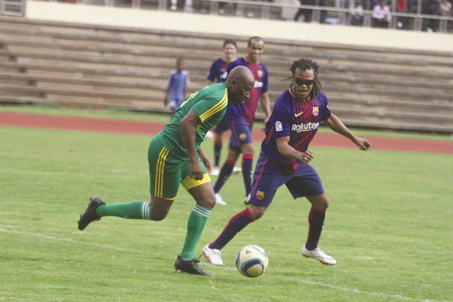 Warriors' legend Peter Ndlovu tries to dribble past former Barcelona midfielder Edgar Davids