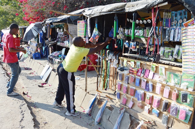 A Plumtree flea market trader, Mr Abraham Ndebele (right), sorts out some of the wares he is selling at his stand in the border town in this file photo