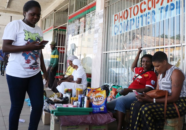 A woman uses EcoCash to pay for groceries sold by a street vendor in Bulawayo yesterday