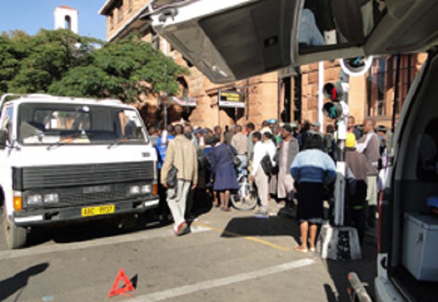 A crowd gathers around the body of a motorist who died in a T35 truck at the robot controlled intersection along Leopold Takawira Avenue and Main Street yesterday, while his truck still remained at the intersection.